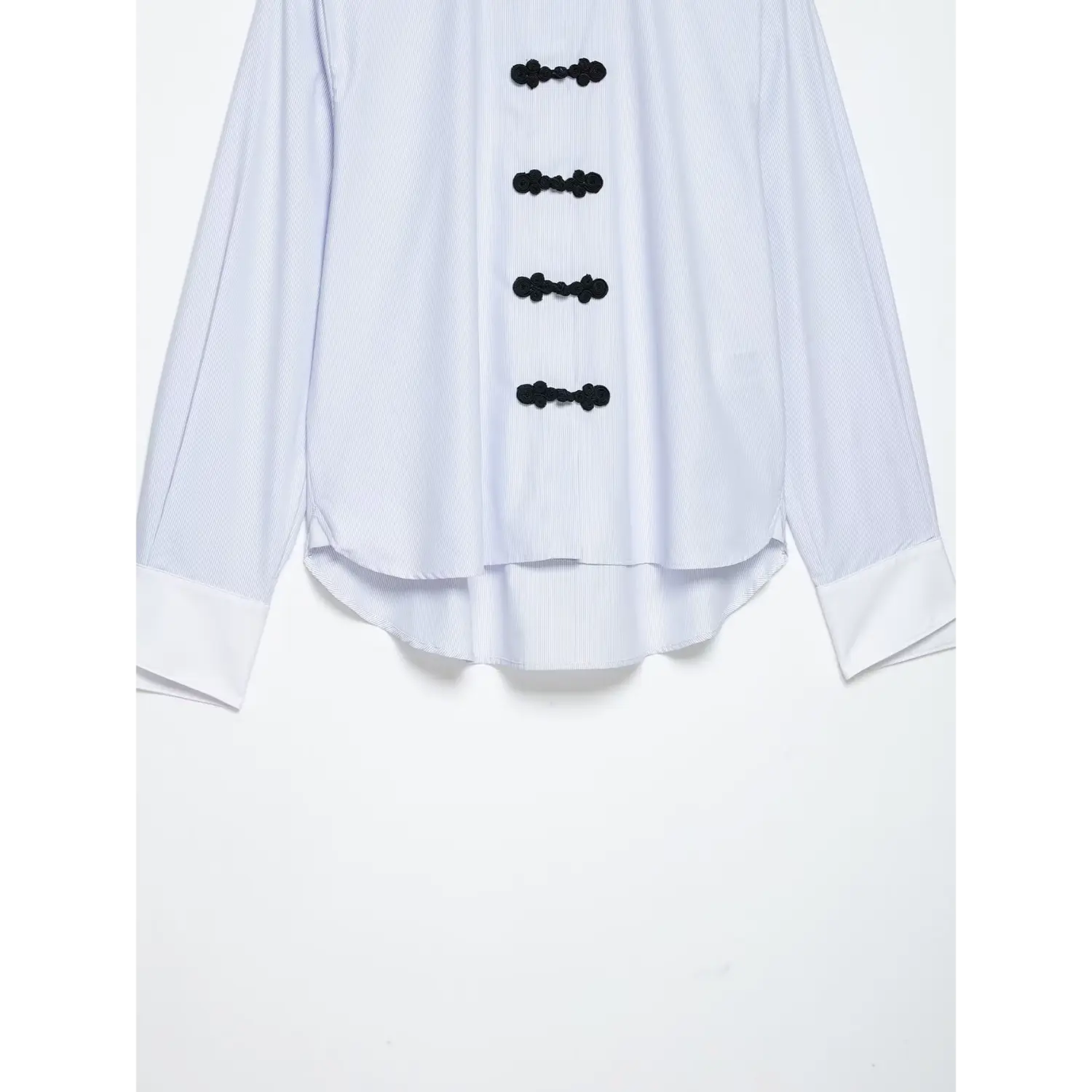 Partial shot of front curved uneven hem, relaxed silhouette and side split detail on pinstripe long sleeve blouse