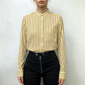 Model wearing stripe stand collar shirt tucked into black high-waisted trousers