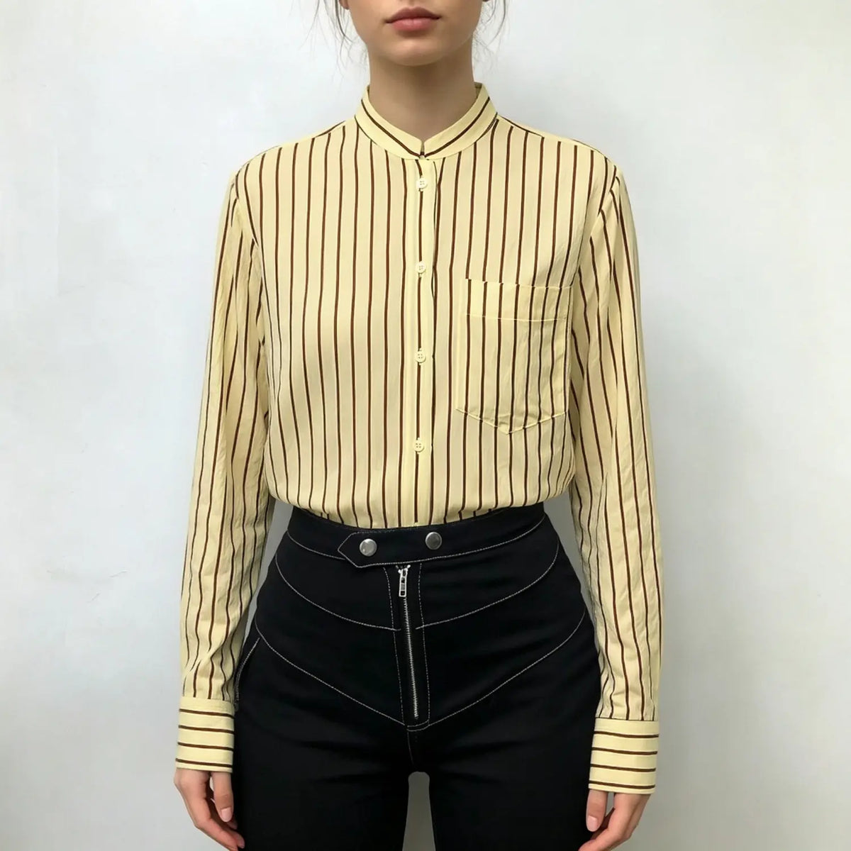 Model wearing stripe stand collar shirt tucked into black high-waisted trousers
