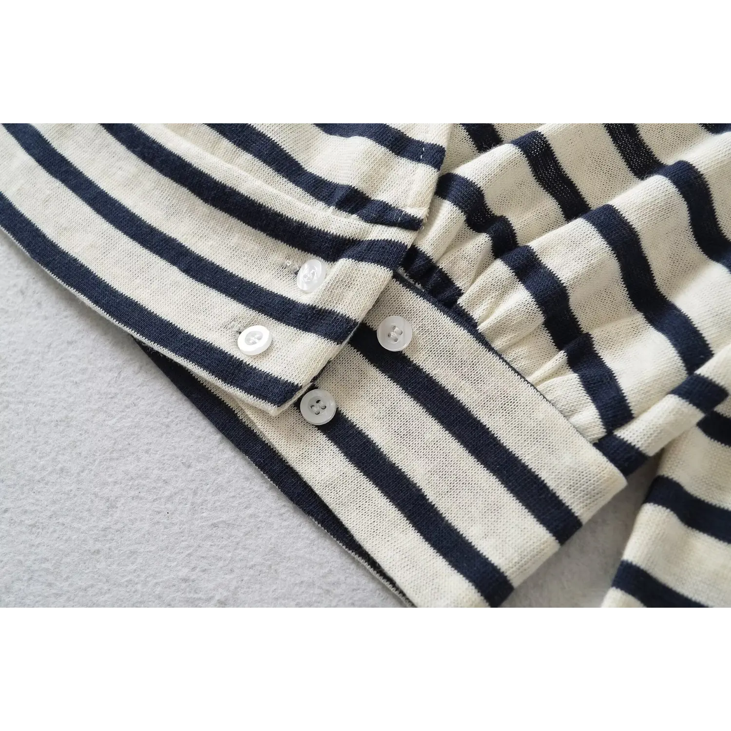 Close-up view of side button details on white navy striped wrap long sleeve cropped top