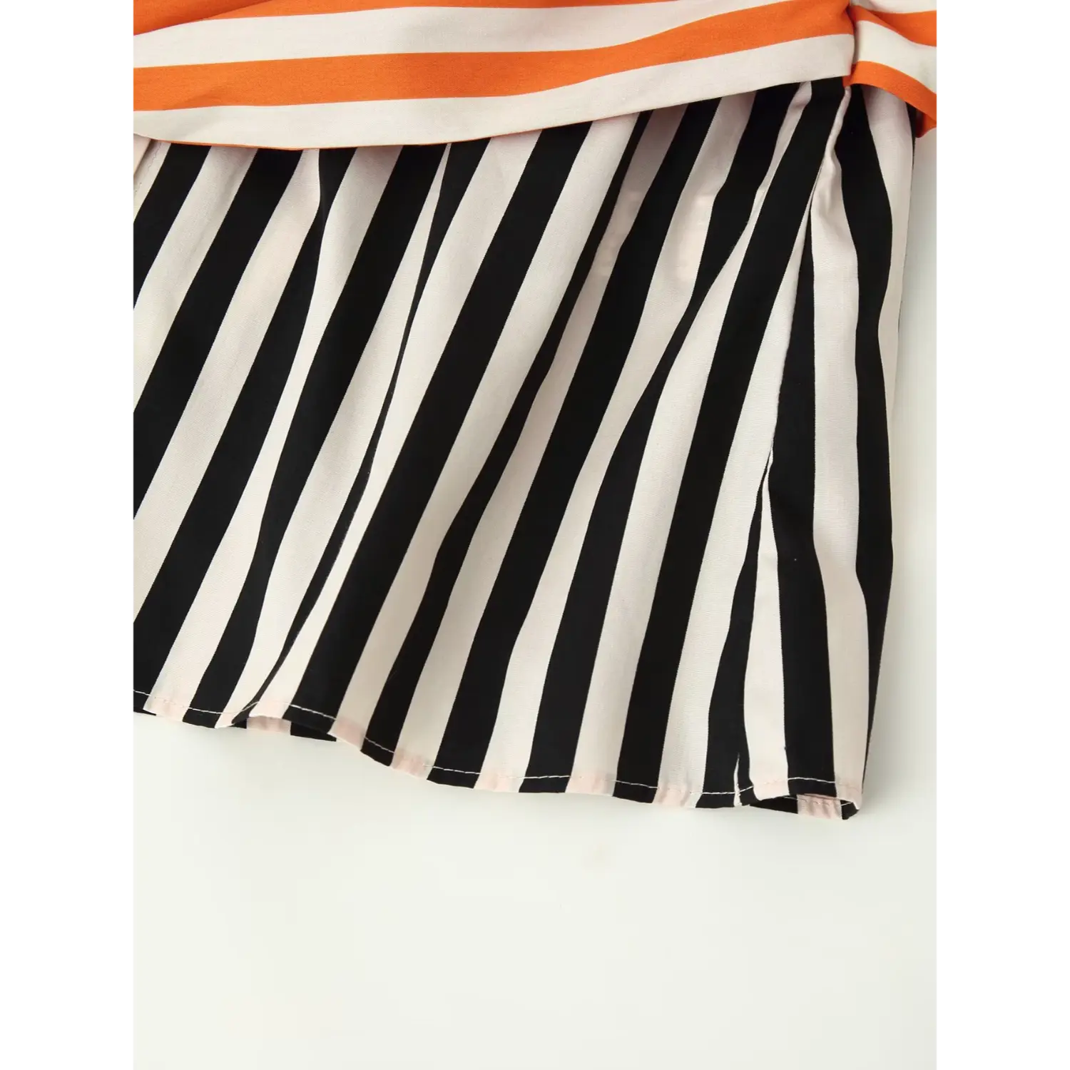 Close‑up of shirt bottom hem, black off‑white vertical stripe fabric, finished neat hem stitching