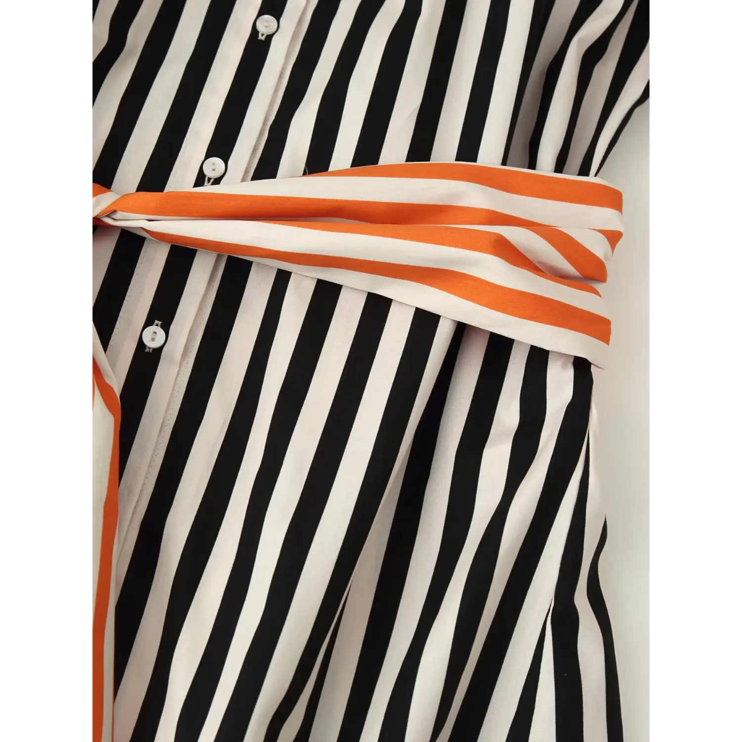 Close‑up of wrapped orange‑white stripe sash on shirt waist, overlay on black‑white striped woven fabric