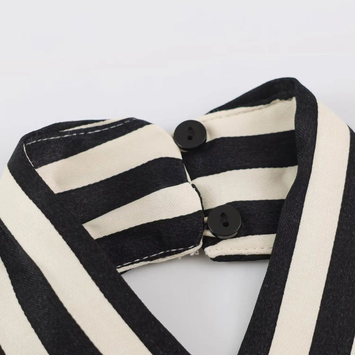 Close-up of two black buttons at back neck