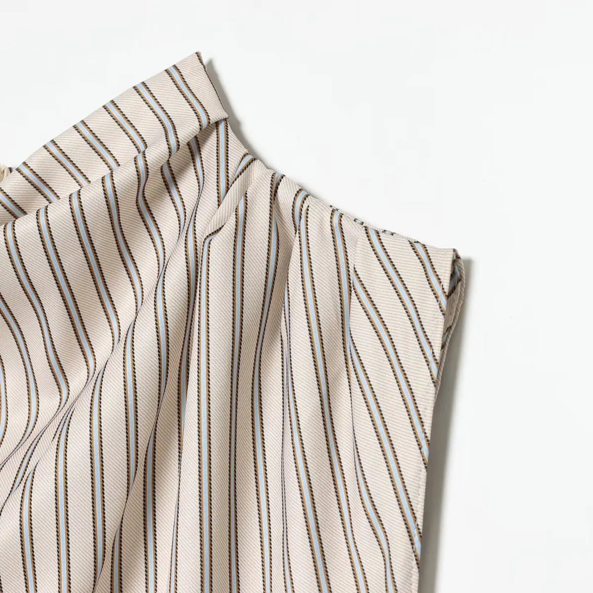 Close-up of the striped fabric on the dress, showing the diagonal pattern with beige, blue, and brown lines
