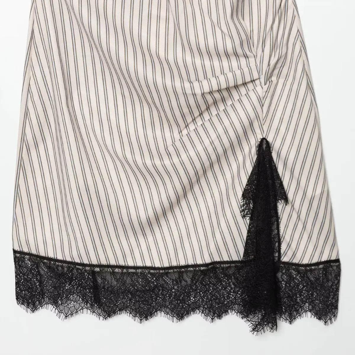 Close-up of the black lace hem and side slit on the striped mini dress, showing the scalloped lace edge