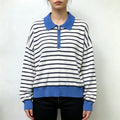 Model wearing striped half zip collared knit top with black trousers