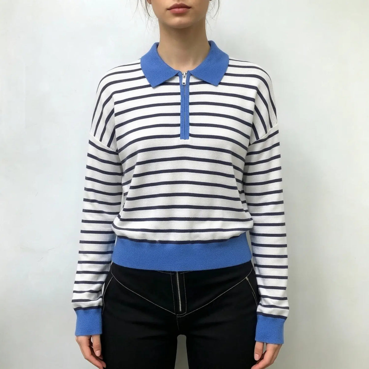 Model wearing striped half zip collared knit top with black trousers
