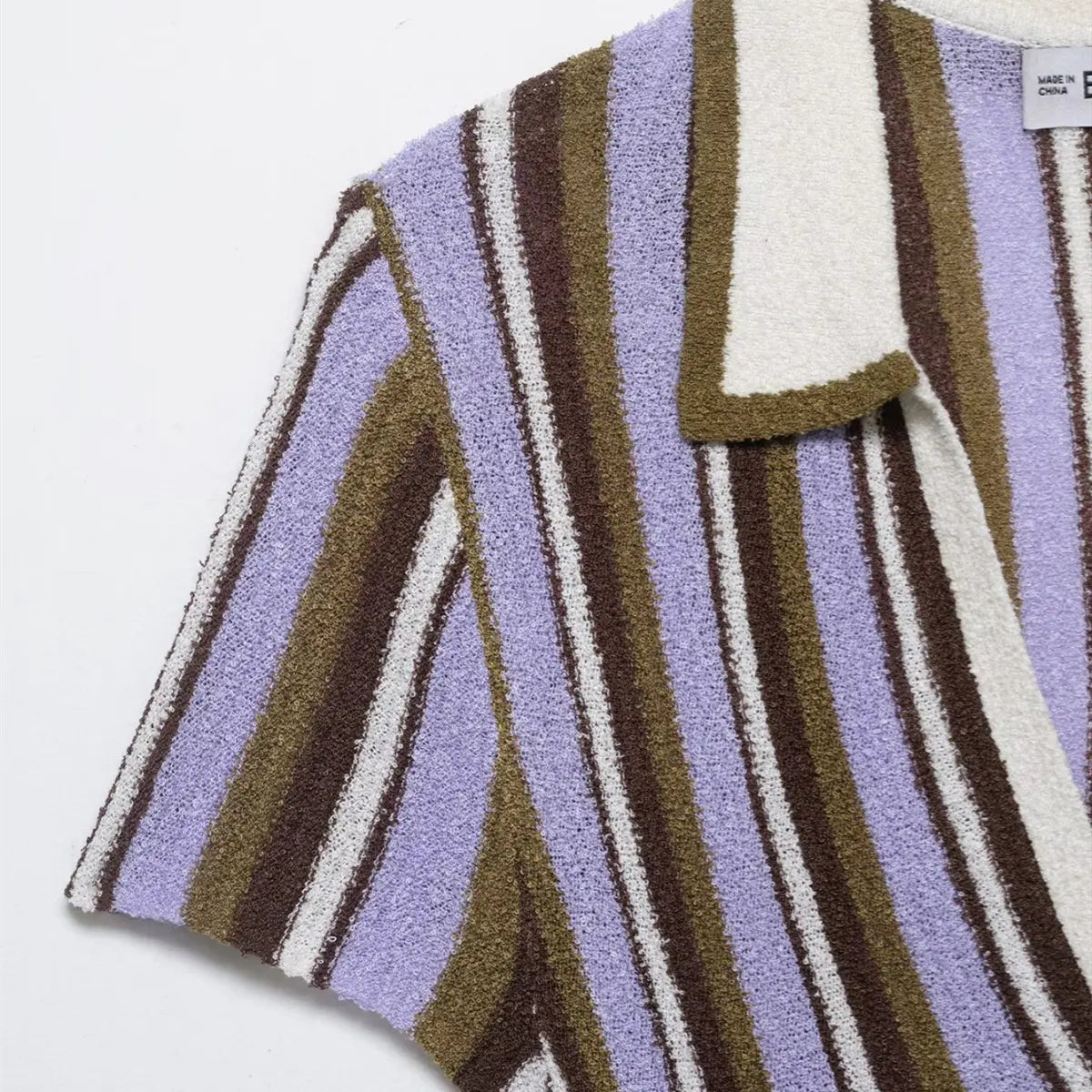 Close-up of the shoulder and short sleeve on the striped knit mini dress, showing the polo-style collar and stripe pattern