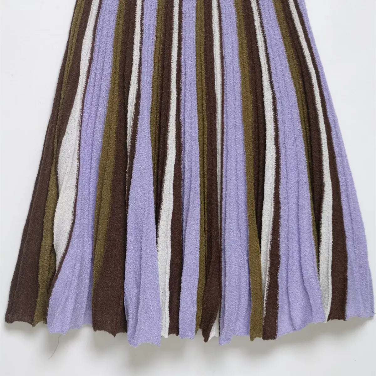 Close-up of the pleated skirt on the striped knit mini dress, showing the vertical stripe pattern and textured knit fabric