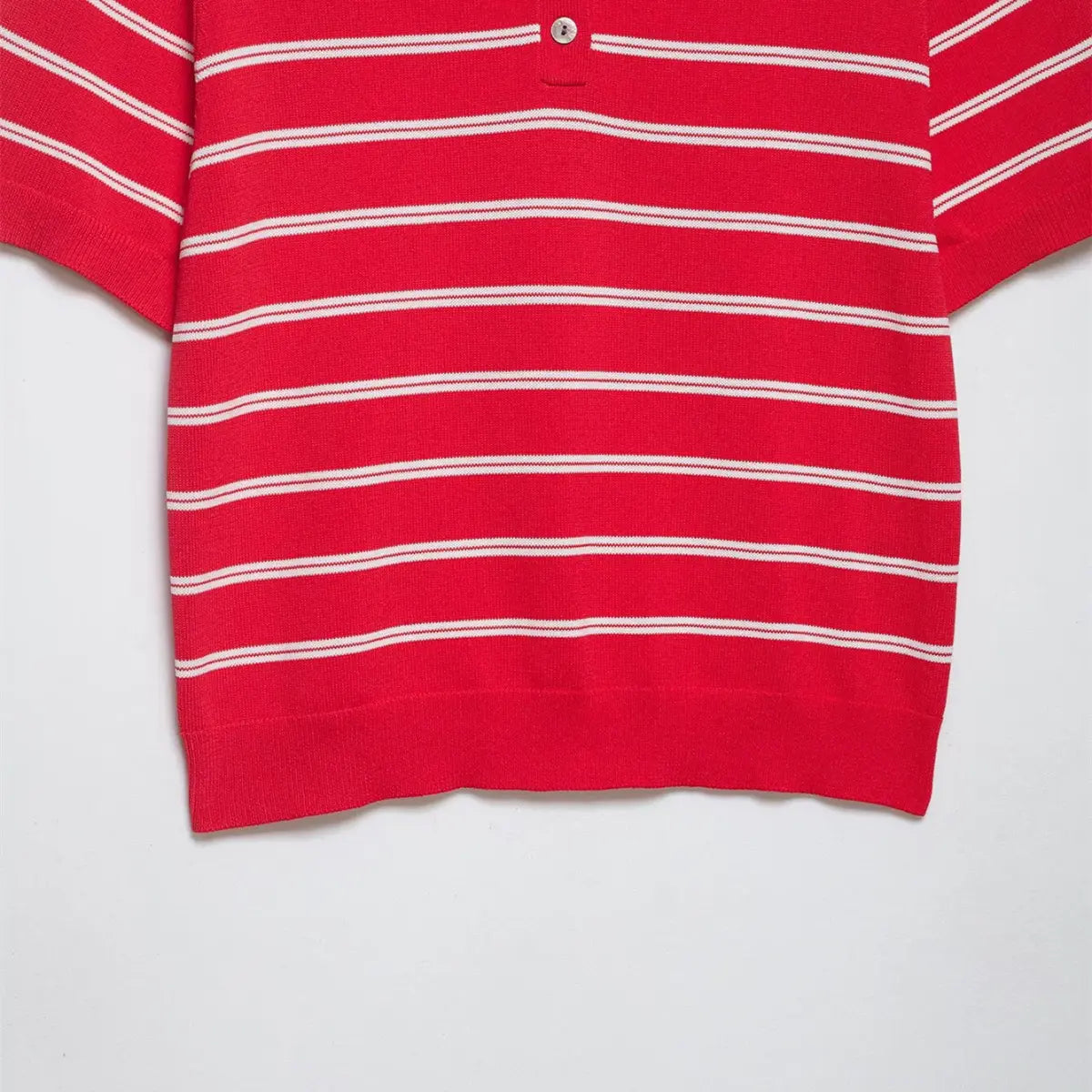 Side view of the red and white striped knit polo shirt, showing the hem and short sleeve ribbing