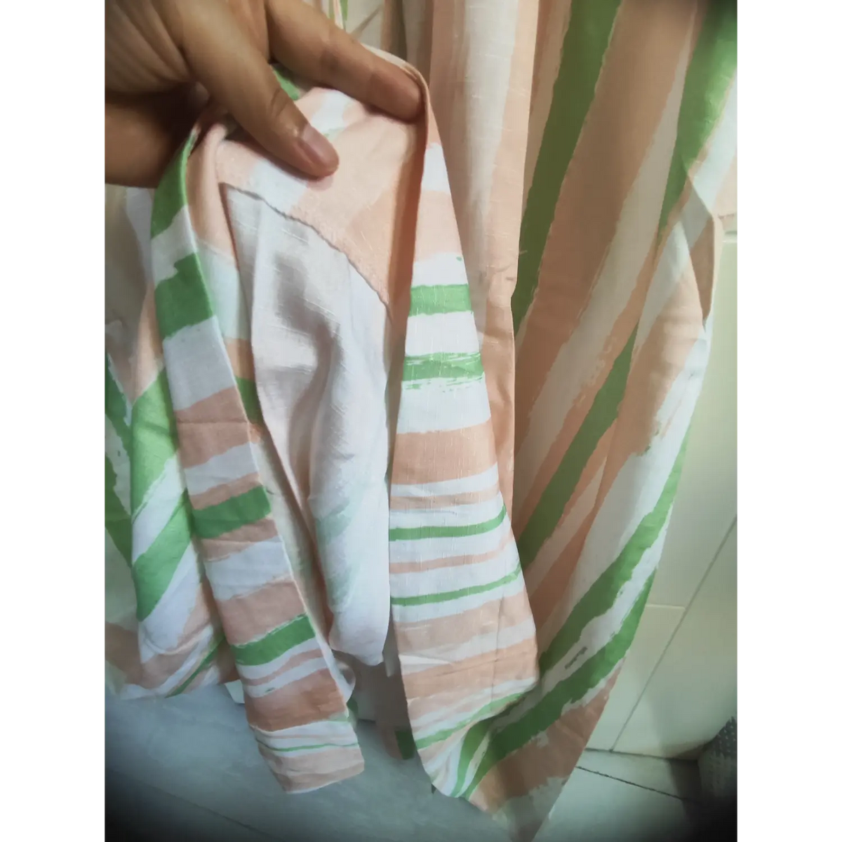 Hand holding fabric of brushstroke stripe maxi dress, showing lightweight woven material texture