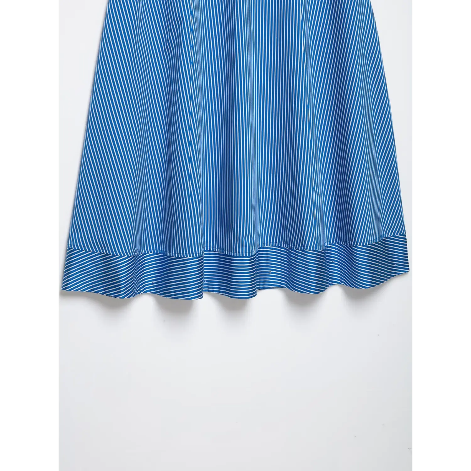 Partial close-up of skirt hem, cascading ruffle frill hem with blue white vertical stripe woven material