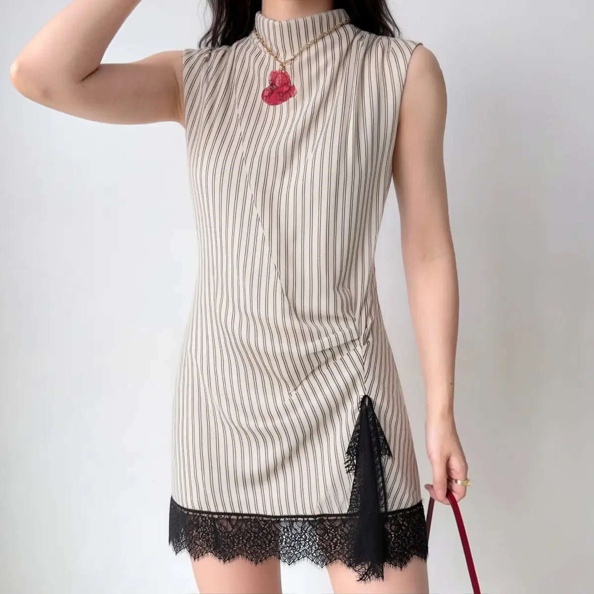 The striped mini dress with black lace hem worn by a model, showing the high neck, draped front, and scalloped lace hem