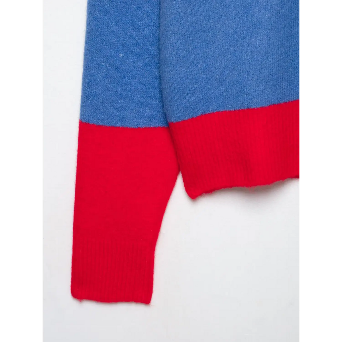 Close-up of blue knit sleeve with red ribbed cuff on striped polo top