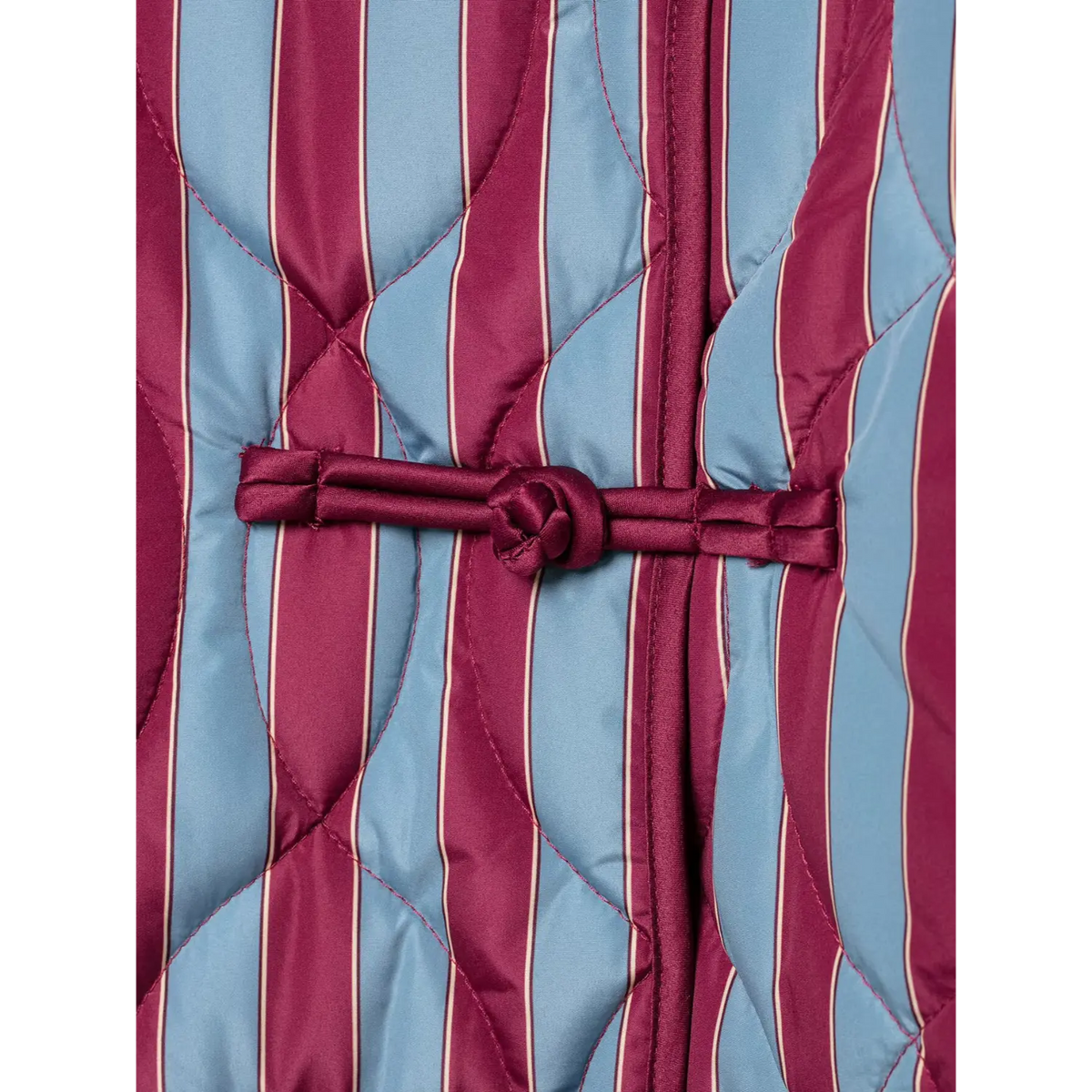 Close-up of wine frog knot button at center front of striped jacket