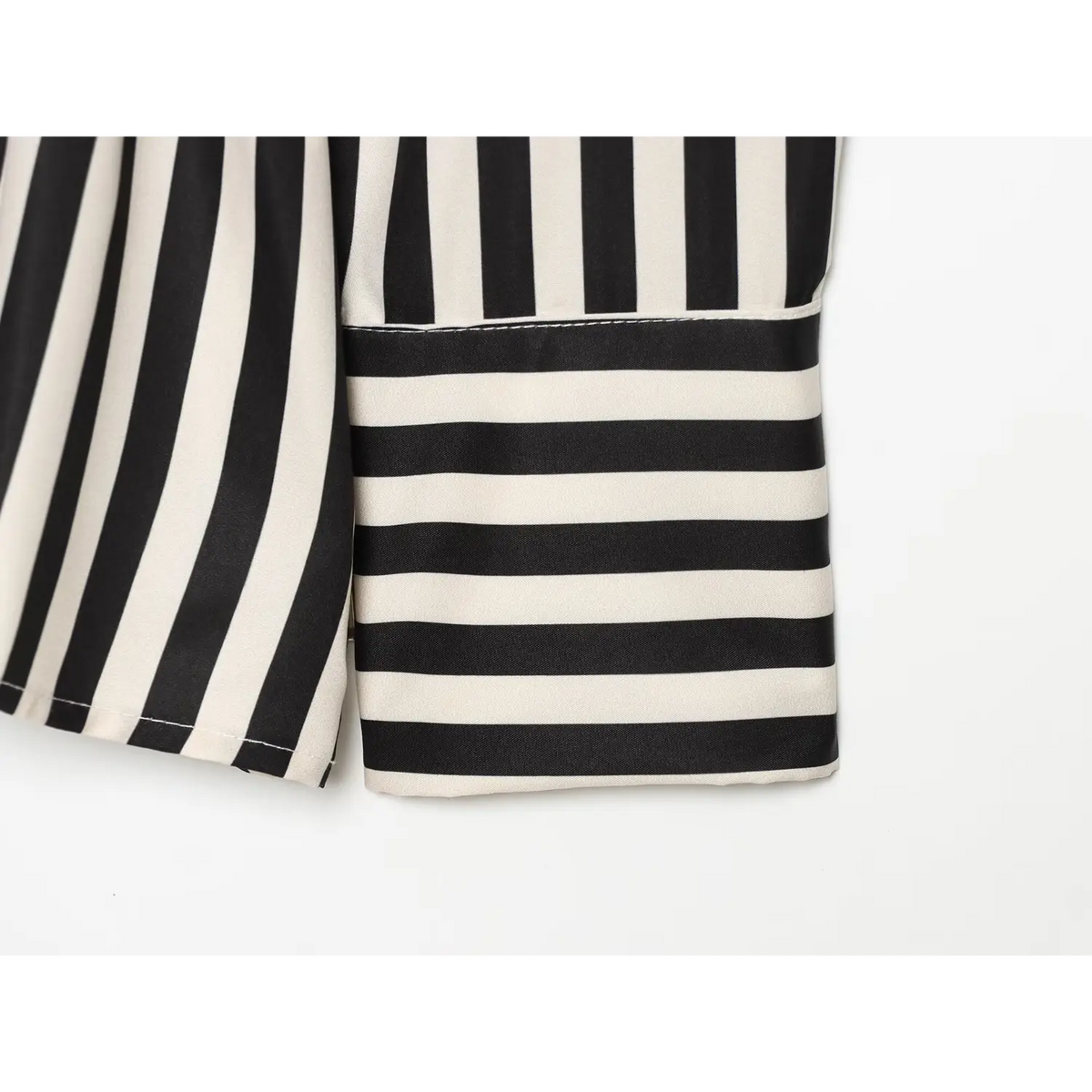 Close‑up of long sleeve cuff, horizontal black‑cream contrast striped cuff, vertical striped shirt body fabric