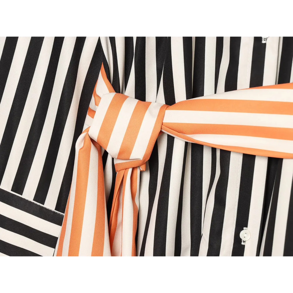 Close‑up of knotted orange‑cream striped wrap belt on black‑cream vertical stripe shirt, belt tie detail