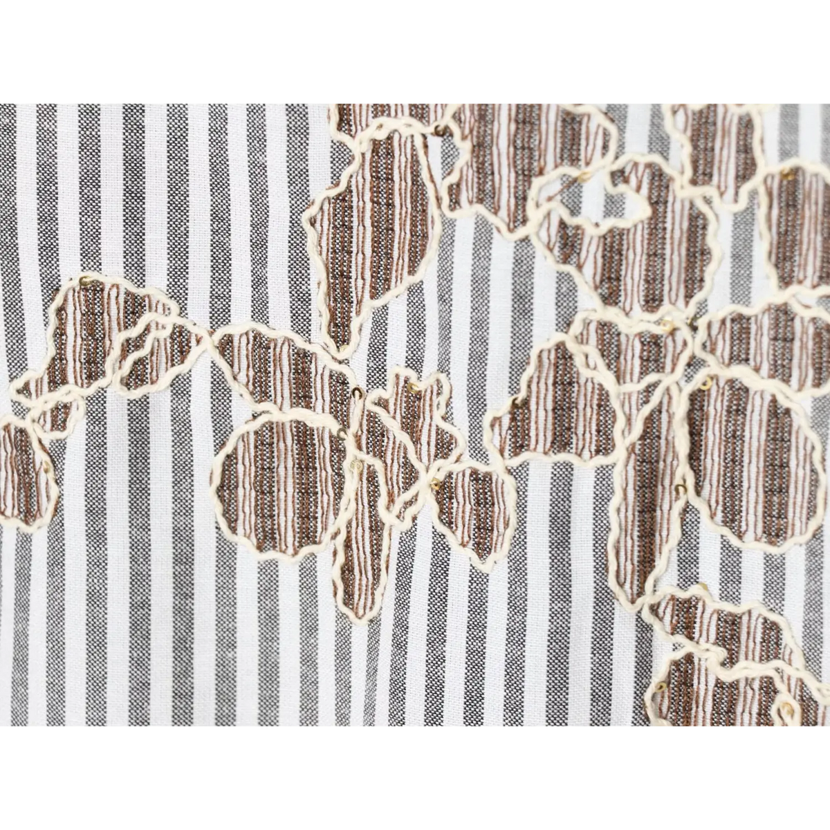 Macro view of floral embroidery over grey‑white vertical stripe woven fabric