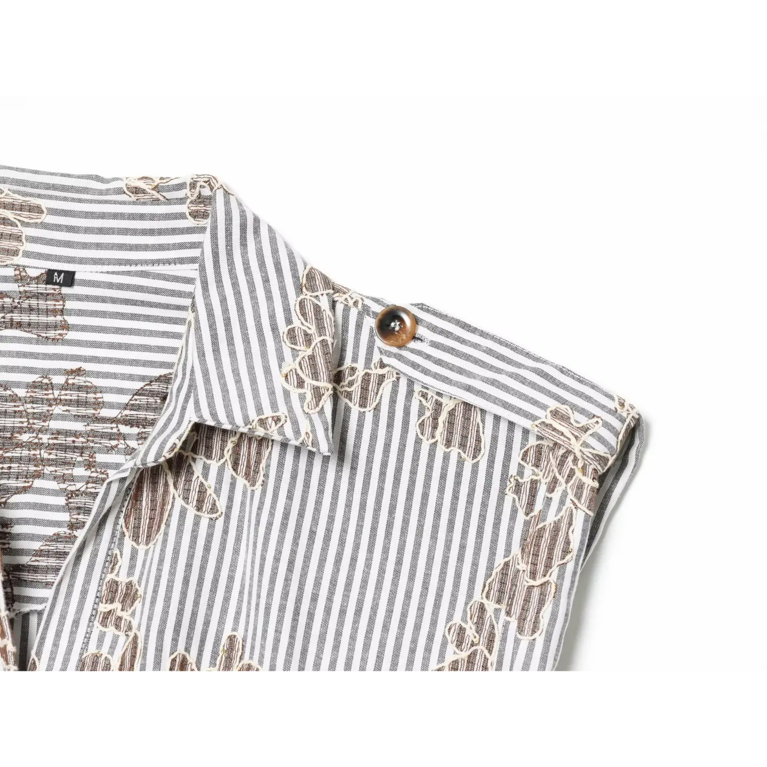 Close‑up shoulder epaulet with tortoiseshell button, sleeveless armhole and floral stripe fabric