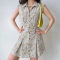 Model wearing sleeveless collared striped floral mini shirt dress with matching fabric belt, hands on hips