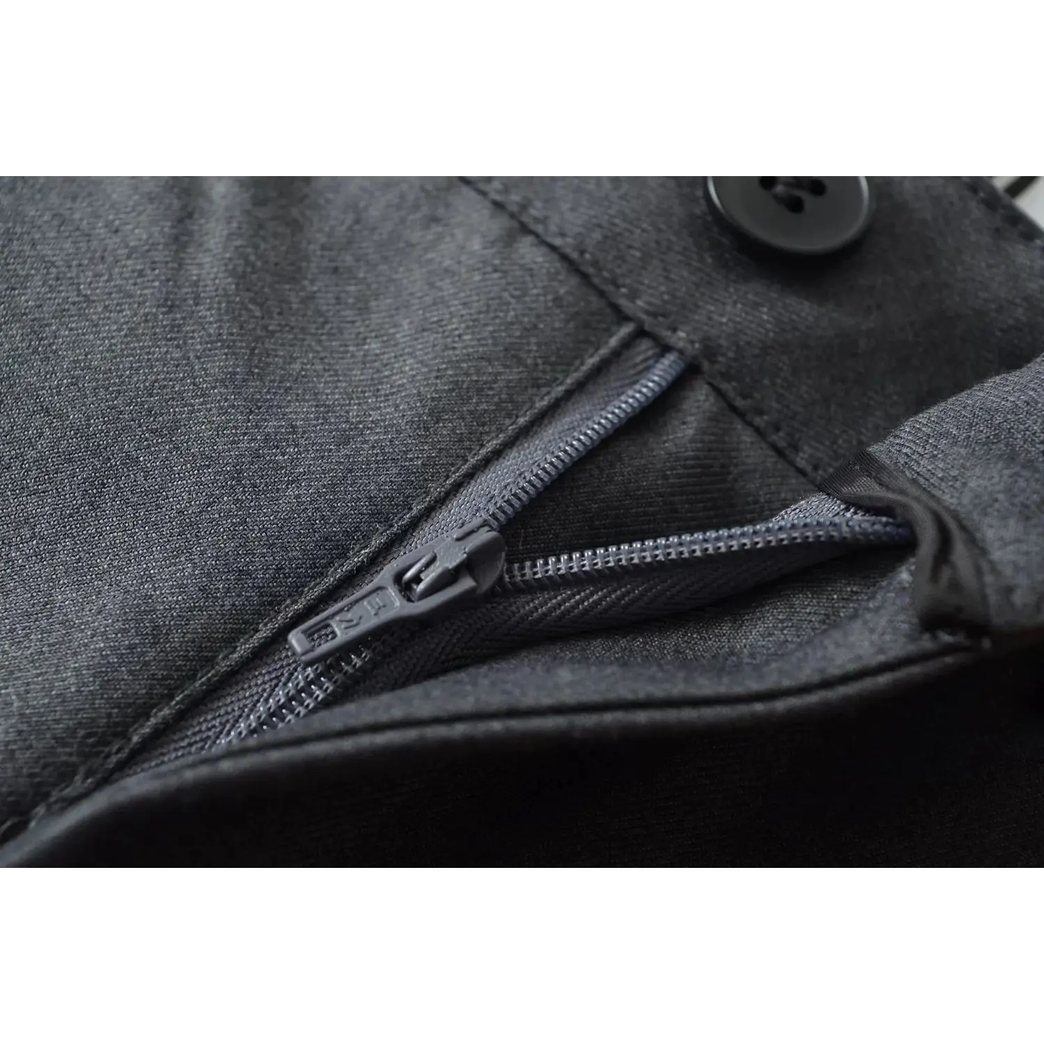 Macro close-up of suit trouser front fly, show durable zipper, round button and woven twill fabric texture