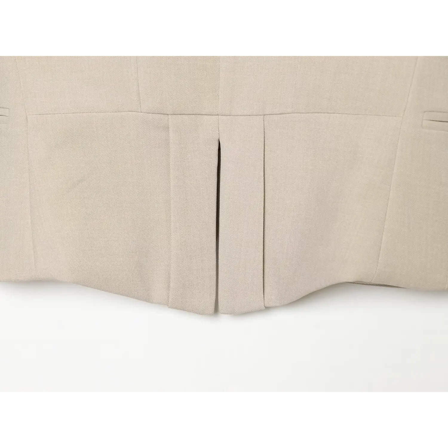 Flat close‑up of back center slit and hem construction on beige waistcoat