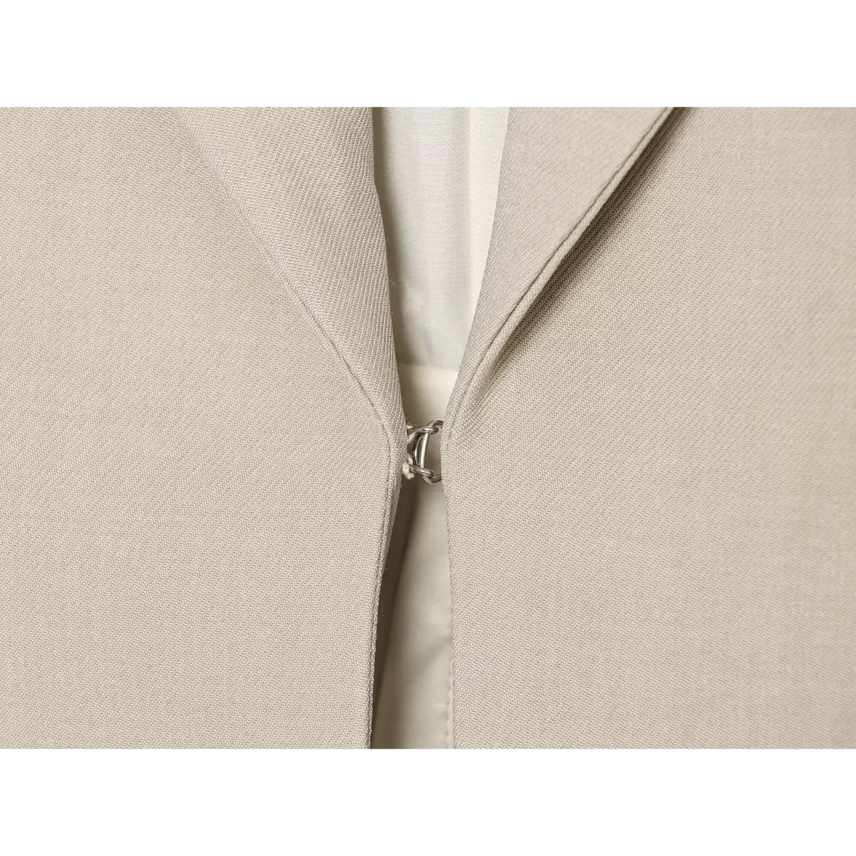 Macro close‑up of front metal hook clasp closure on tailored vest