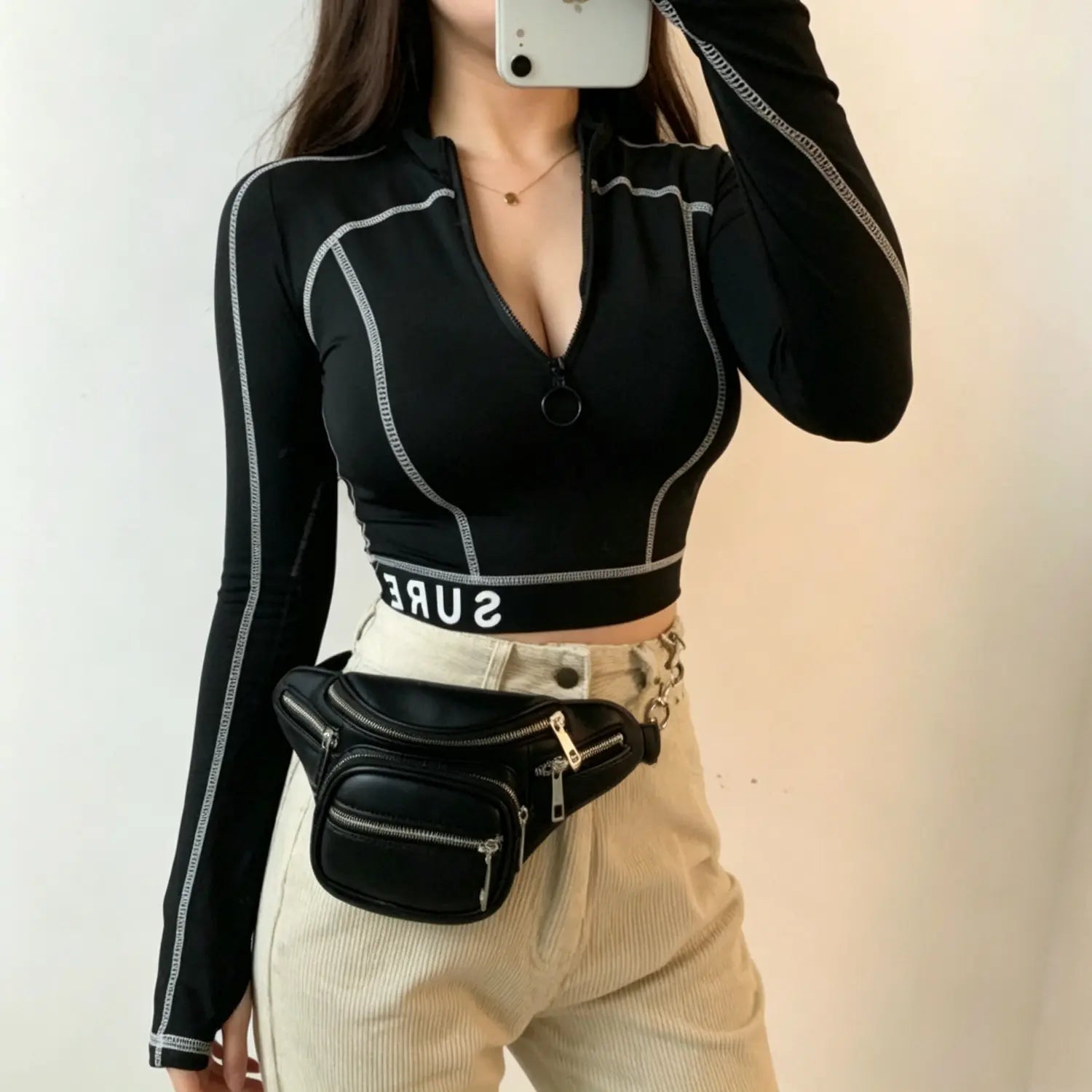 Selfie model wearing black contrast stitching half zip long sleeve crop top paired with beige jeans
