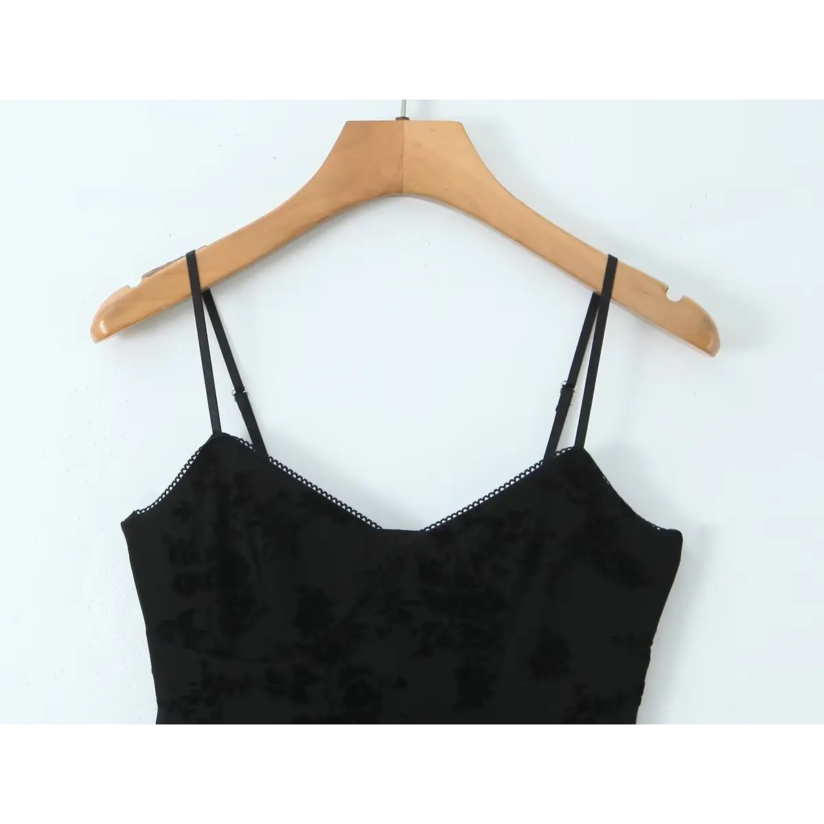 Close-up of the sweetheart neckline on a black flocked floral slip dress, showing the delicate lace trim and adjustable spaghetti straps.