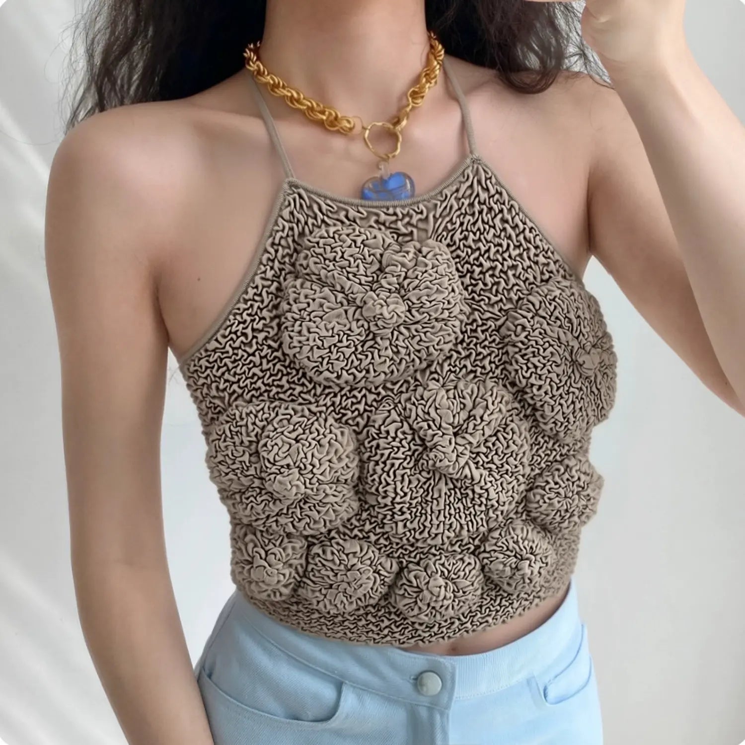 Lifestyle wearing shot of taupe textured bubble knit camisole top with floral pattern, paired with light blue denim jeans