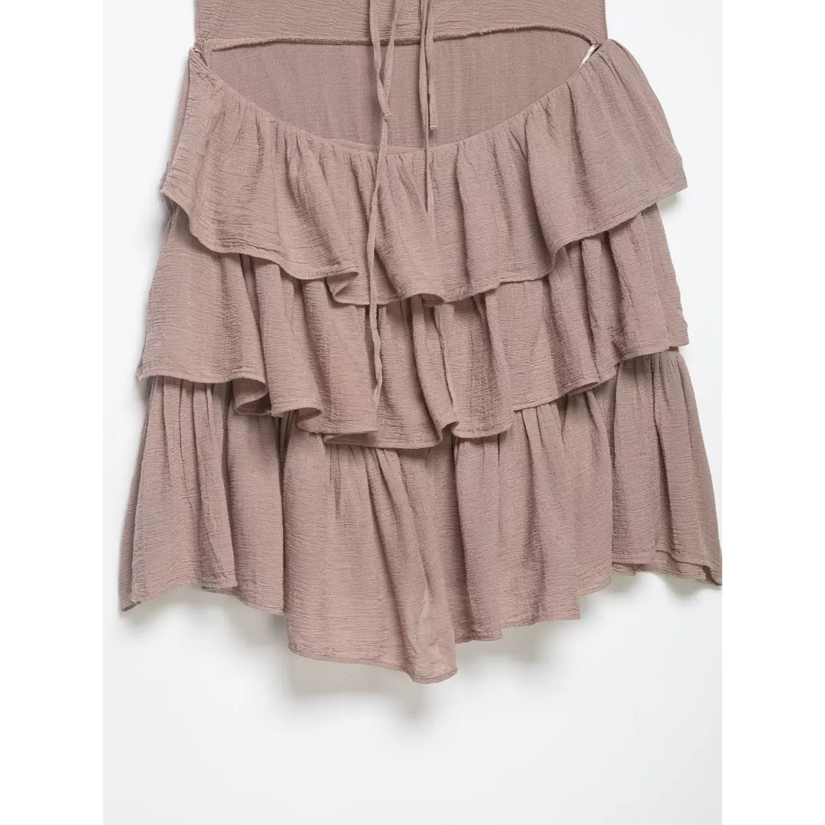 Close-up of the tiered ruffled skirt and lightweight fabric texture on the taupe halter dress