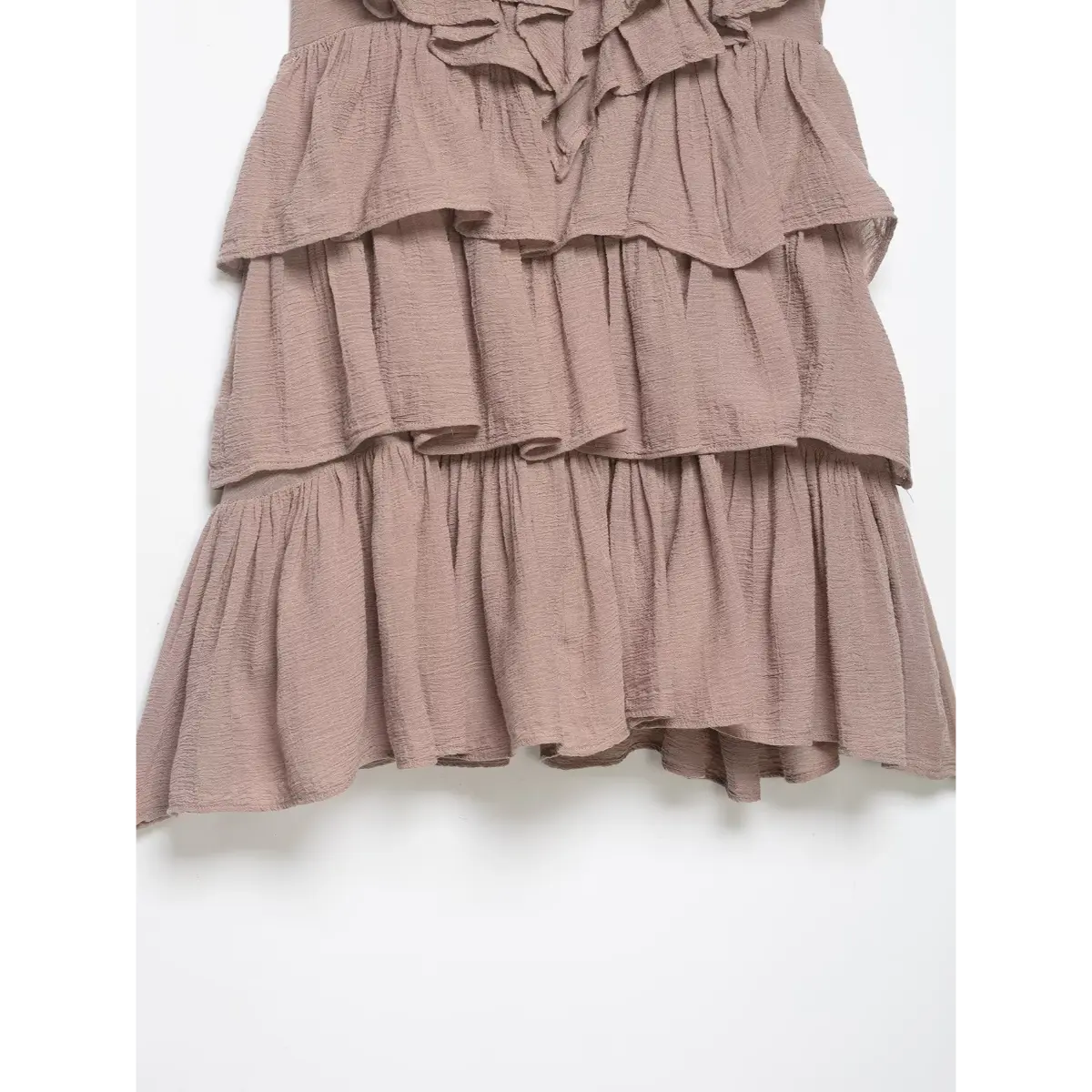 Close-up of the tiered construction and ruffled hem on the taupe halter dress