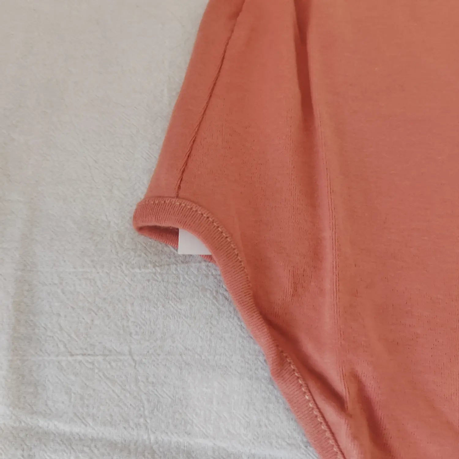 Close‑up armhole finished stitching detail of terracotta knit bodysuit