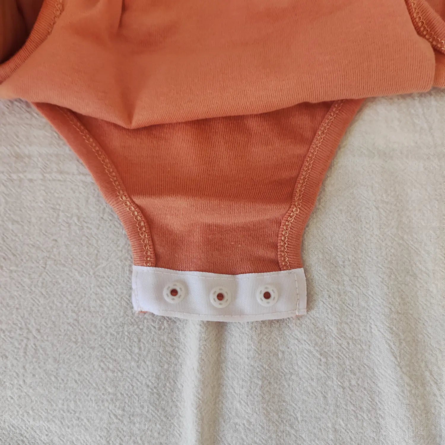 Close‑up inner crotch seam and fabric construction of terracotta scoop neck bodysuit