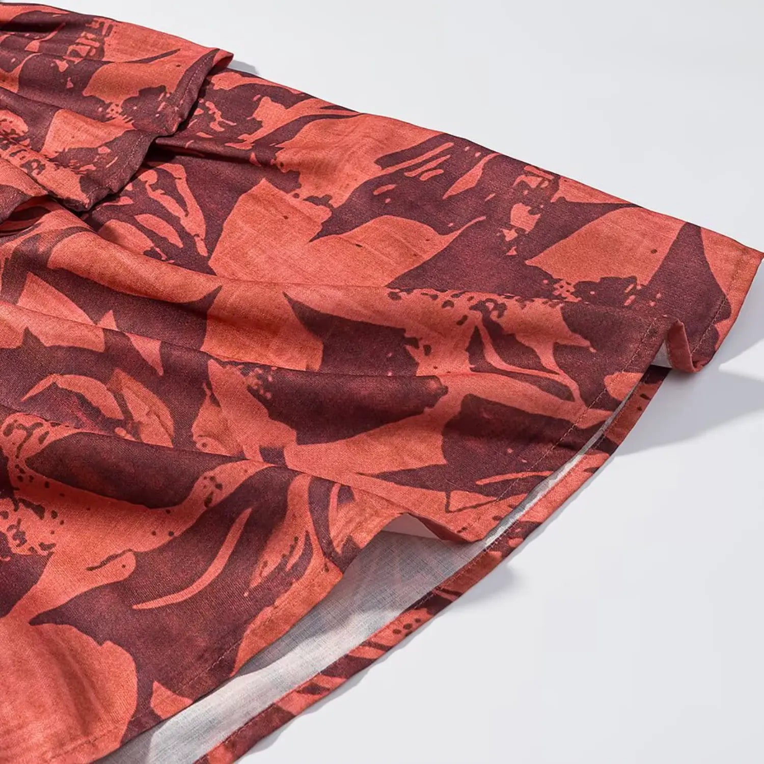Detailed shot of tiered ruffle hem, fabric print and inner lining of terracotta floral midi dress