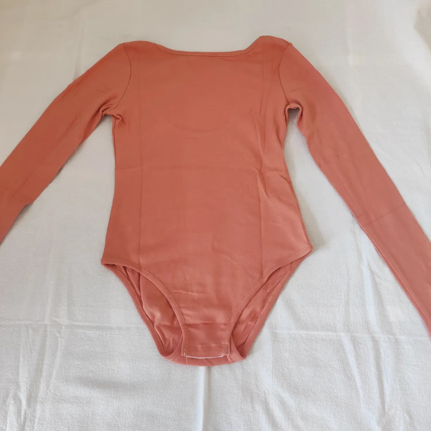 Flat lay front view terracotta solid scoop neck long sleeve snap‑crotch bodysuit