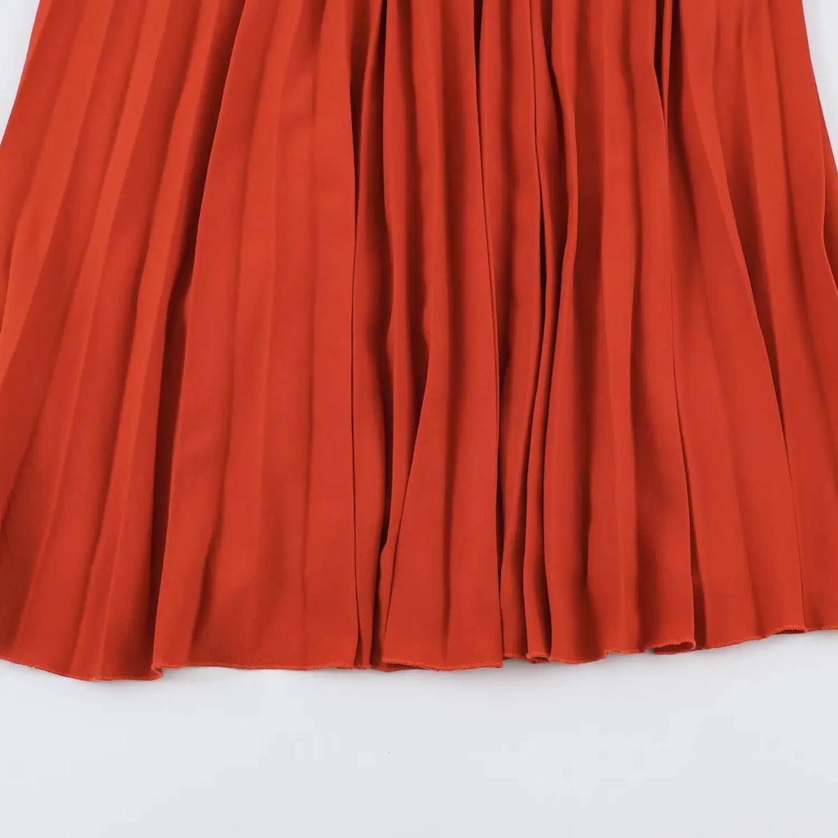 Close‑up of deep vertical pleats on terracotta maxi skirt hem