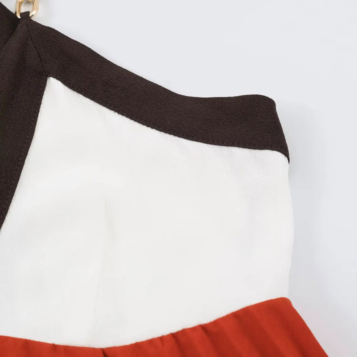 Close‑up of stitching seam on terracotta‑white color‑block bodice panel