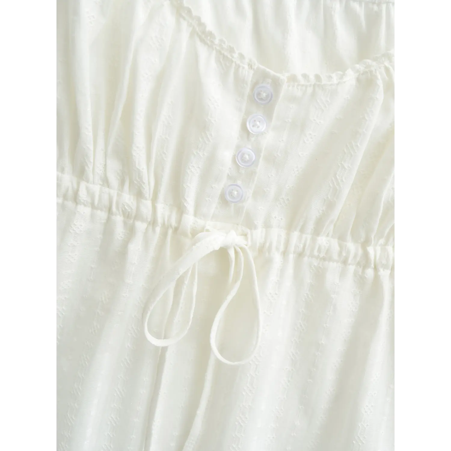 Close-up of the button placket and drawstring waist on a white textured camisole