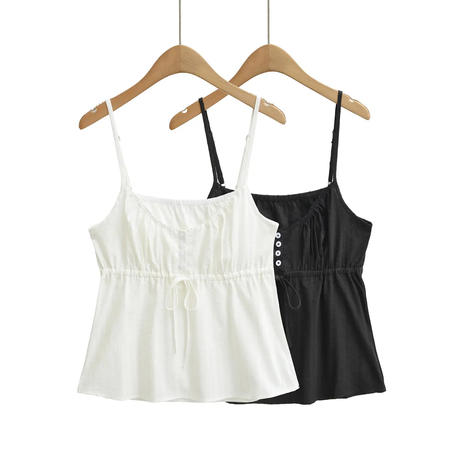  White and black textured camisole tops hanging on wooden hangers, showing front view