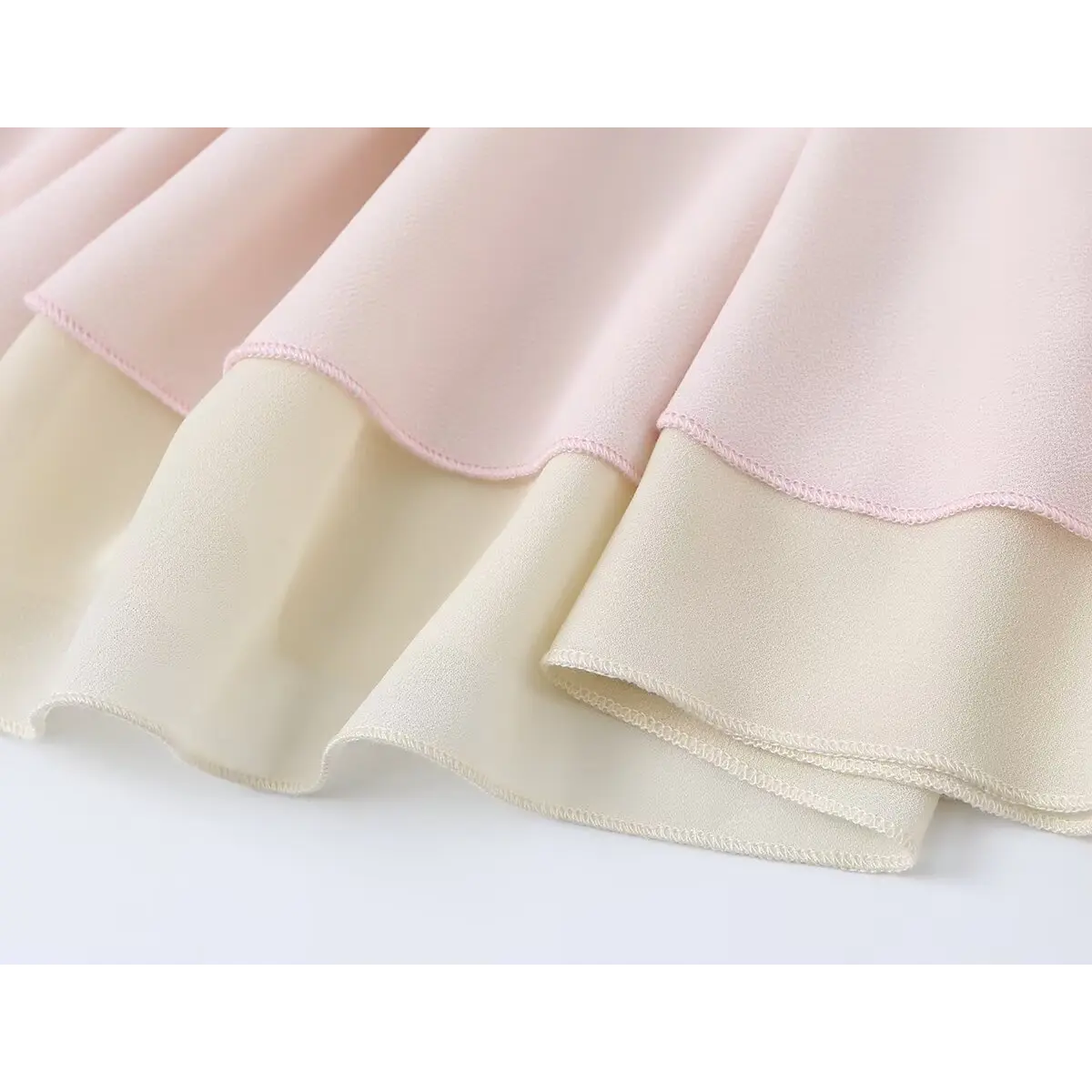 Close-up view of the layered hem on a pink and beige tiered chiffon skirt, showing the double-stitched edges.