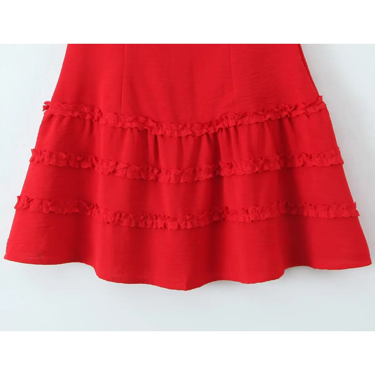 Close-up of the tiered lace skirt on a red cami dress, highlighting the ruffled lace trim and layered construction.