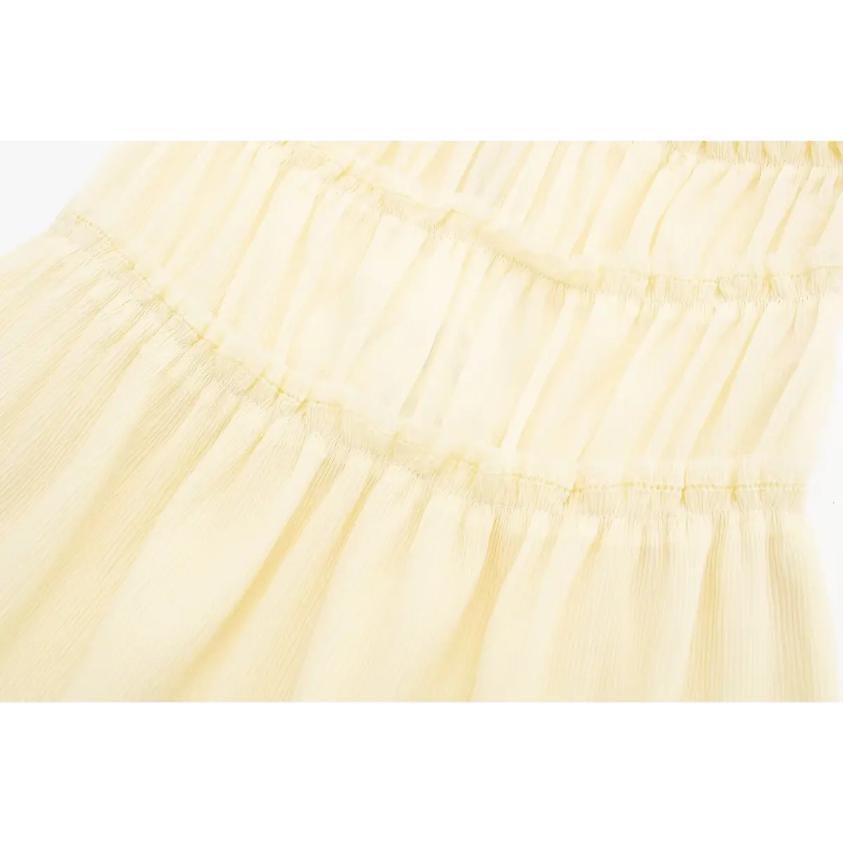 Close-up of the tiered smocked construction on a cream cami dress, highlighting the gathered fabric and delicate stitching.