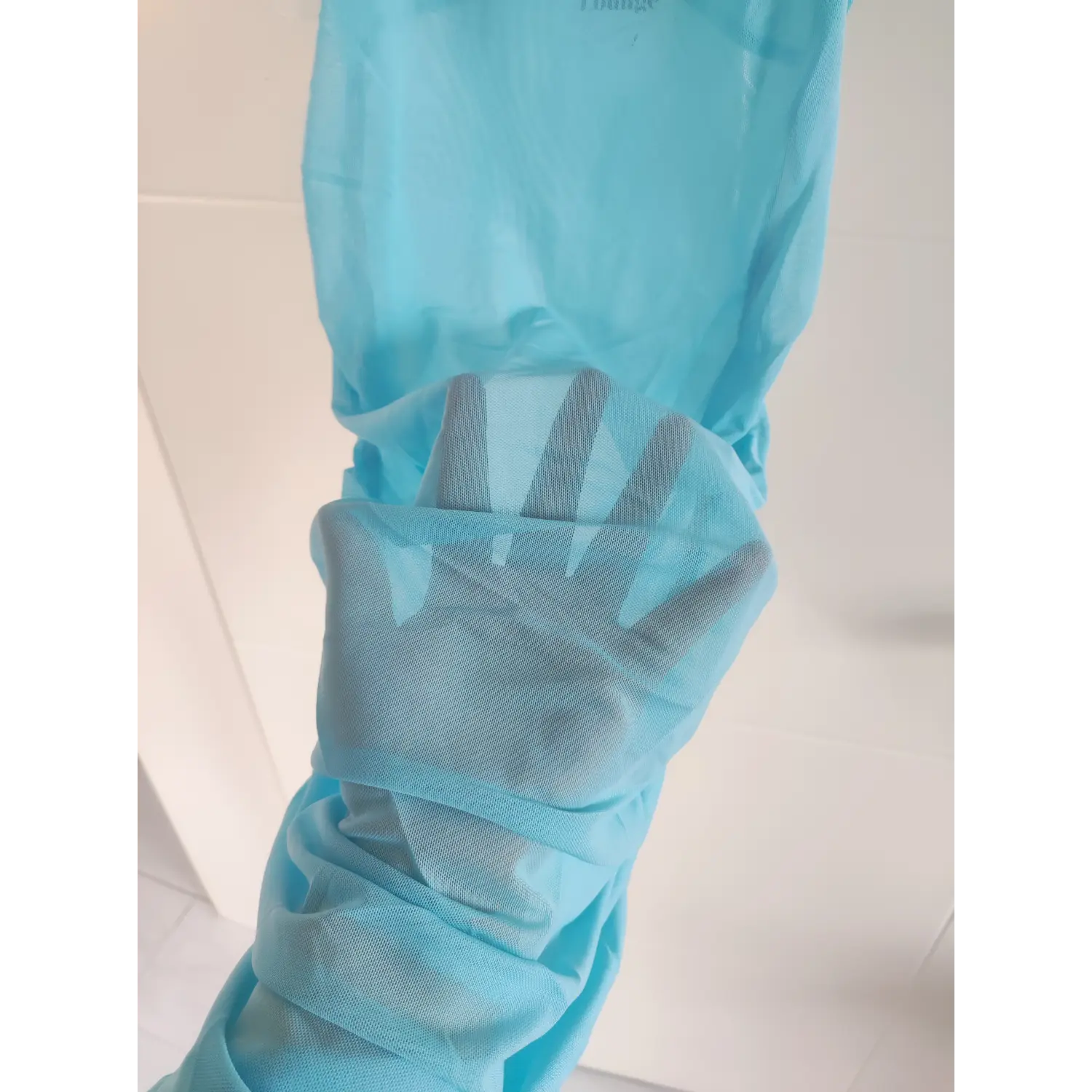 Transparency test photo of light blue stretch mesh fabric, hand behind sheer fabric to show semi-transparent texture
