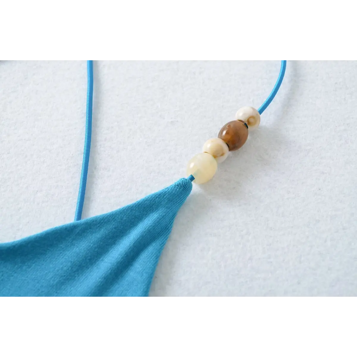 Close-up of the brown and cream beads on the strap of the turquoise camisole