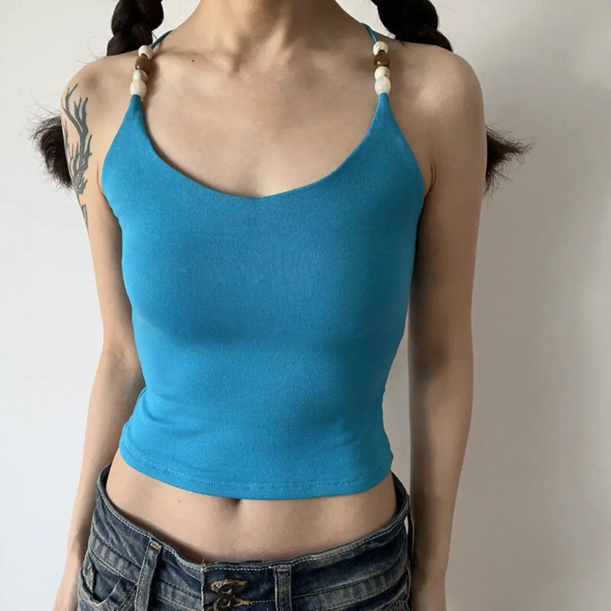 Lifestyle shot of turquoise ribbed camisole with beaded straps and crisscross back
