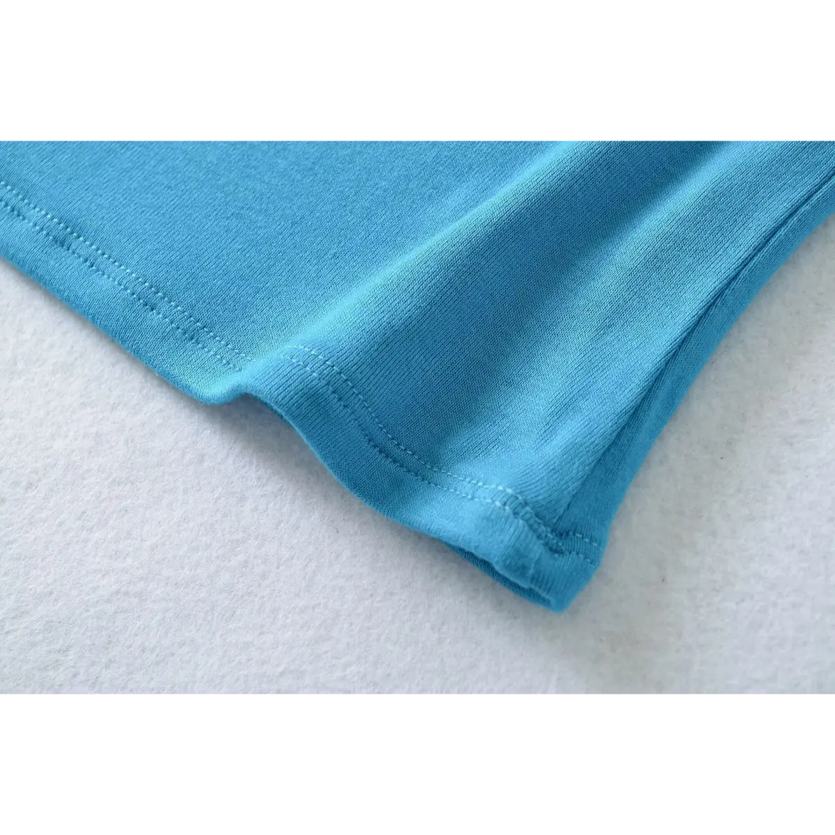 Close-up of the side hem stitching on the turquoise ribbed camisole top