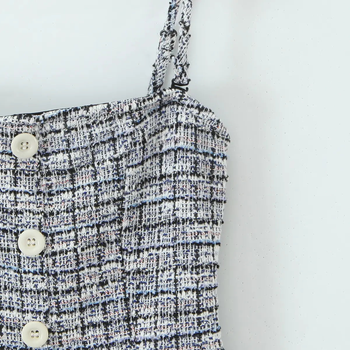 Close-up of the front white buttons, shoulder strap construction, and tweed fabric texture.