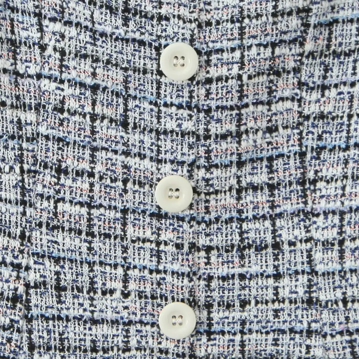 Close-up of the three white buttons and woven tweed pattern on the dress front.