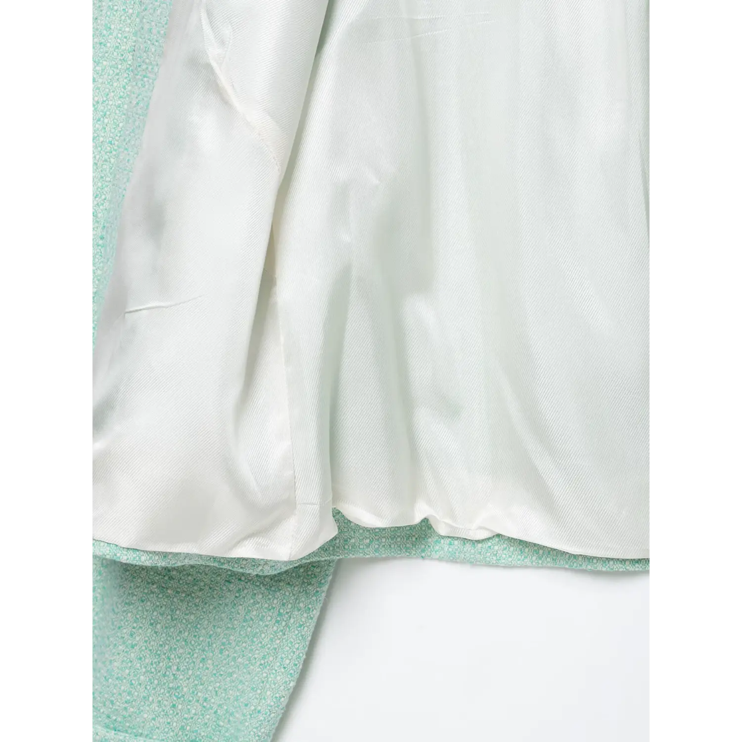 Interior view smooth white satin lining of mint woven short coat, fabric hem stitching detail